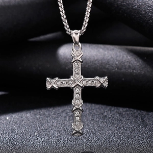 Macro shot of silver titanium cross pendant with X patterns and crystals on dark velvet