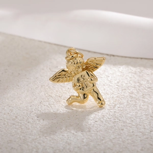 Macro shot of gold-plated cupid angel pendant with wings on textured stone background
