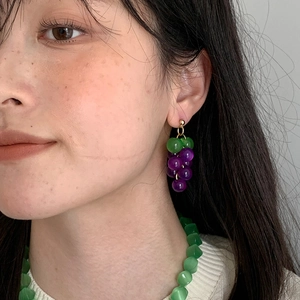 Detail shot of sweet purple and green resin grape tassel earrings worn by a model.