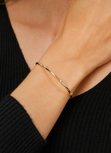 Detailed close-up of a minimalist gold-plated brass cuff bracelet with three small zircons