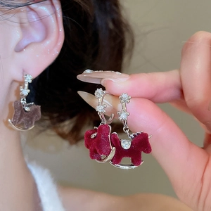 Detailed close-up of red flocked rocking horse earrings with sparkling zircon accents