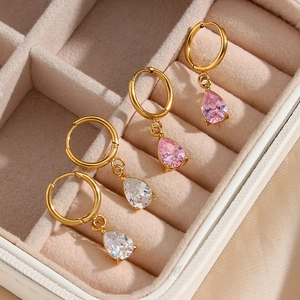 Pendientes dorados con circonitas rosas y blancas en un joyero de color beige