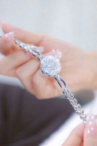 Close-up of silver camellia bracelet watch with shimmering crystals on woman wrist