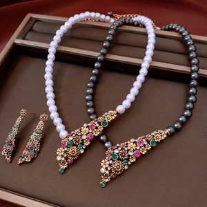 Dettaglio di collane di perle vintage con pendenti a fiore e orecchini abbinati
