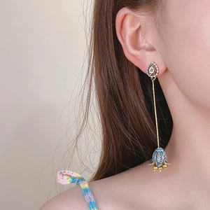 Vintage flower drop earrings with blue petals and gold beads on a female model