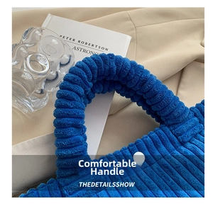 Detail of blue corduroy tote bag featuring thick handles and a white button closure