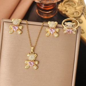 Golden bear jewelry set with pink heart stones and clear zircons on silk background