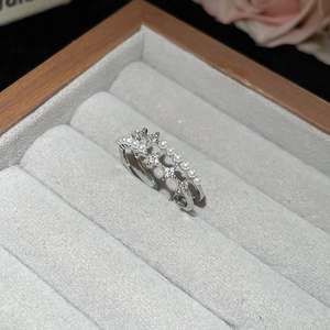 Macro detail of silver ring with pearls and zircon star motifs on a velvet display