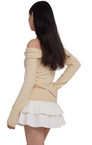 Detailed side view of beige off-shoulder knit top with irregular cut and long sleeves