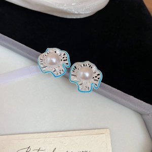 Detailed macro view of S925 silver pearl stud earrings with blue enamel flower petals