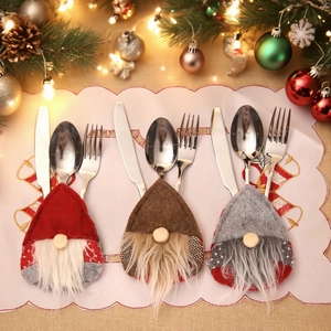 Three gnome Christmas cutlery holders with stainless steel utensils on festive background