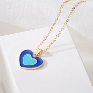 18K gold plated necklace with blue and turquoise enamel heart pendants on a white cube