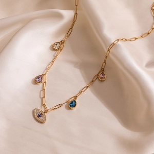 Gold evil eye necklace with colorful pear-cut zircon teardrop pendants on silk backdrop