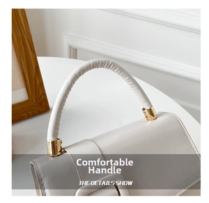 Detail view of smooth rounded handle and gold metal accents on minimalist handbag