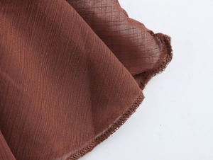 Dettaglio del tessuto in chiffon marrone che mostra cuciture fini e l'orlo bohémien