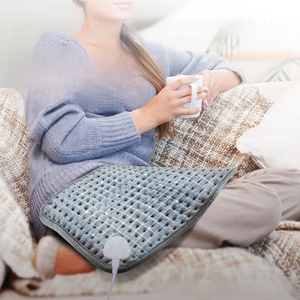 Macro detail of soft grey heating pad showing breathable fabric and power connector