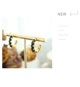 Détail de boucles d'oreilles en C plaquées or 18K avec zircons vert émeraude