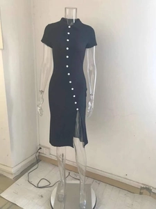 Detail of black slim fit dress featuring a diagonal white button row and side slit design