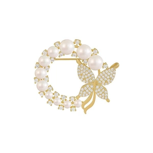Close-up of golden circle brooch with white pearls, small diamonds and a crystal butterfly