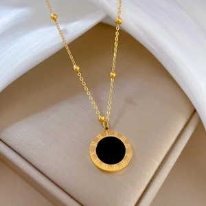 Detailed macro view of the Roman numeral engraving on a gold and black shell pendant