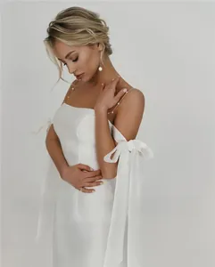 Detail of white satin wedding dress with pearl straps and elegant arm bow accents