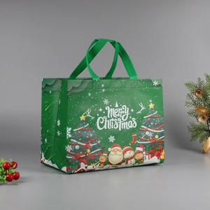 Close-up of green Christmas non-woven tote bag with Santa and reindeer cartoon patterns
