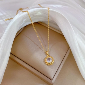 Detailed close-up of a gold rotating zircon necklace on soft white silk fabric
