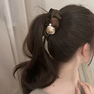 Close-up of vintage satin rose flowers and pearl on a premium banana hair clip