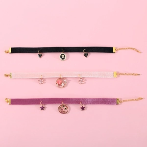 Velvet pet collars with gold pendants in black, pink, and purple on a soft pink background