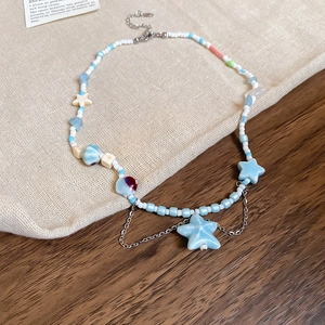 Detailed view of light blue star charms and beaded necklace with fringe chains