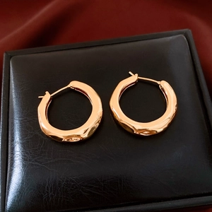 Macro detail of gold plated hammered round earrings on a premium black leather jewelry box
