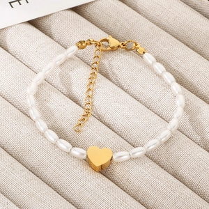 Detail of beaded pearl bracelet featuring a golden heart pendant and lobster clasp
