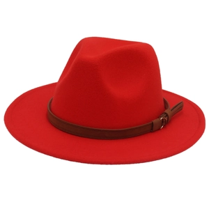 Detailed macro view of bright red wool fedora hat with brown leather decorative belt