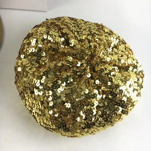 Top view of a gold sequin beret hat showing detailed shimmering texture on white background