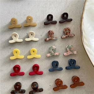 Detailed view of colorful acetate mini hair claws in various patterns on a grey surface