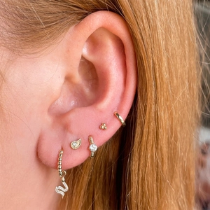 Close-up of S925 sterling silver snake pendant earrings and rhinestone studs on ear