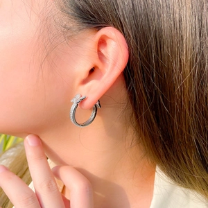 Close-up of model wearing silver butterfly hoop earrings with sparkling rhinestones