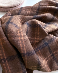 Macro view of thick brown plaid scarf fabric with orange and black checkered weave texture