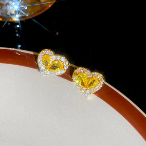 Macro shot of yellow heart-shaped zircon earrings with gold plating and white stones