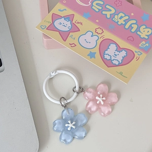 Flat lay of blue and pink jelly cherry blossom keychains on a desk with cute accessories