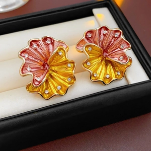 Macro shot of vintage metal flower earrings with red enamel and inlaid rhinestones