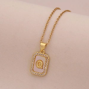Vue macro du pendentif lettre Q en or 18 carats avec nacre blanche et cristaux brillants