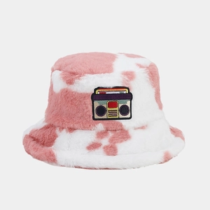 Detail of pink cow print plush bucket hat featuring a retro radio embroidered patch