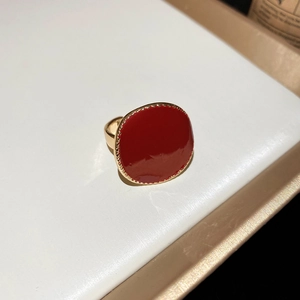 Détail d'une bague dorée vintage avec une grande pierre émaillée ovale rouge et bordure dorée
