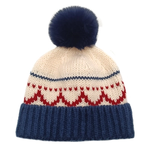 Dettaglio cappello invernale in maglia con grande pompon blu e motivi jacquard