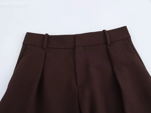 Detail der dunkelbraunen Anzughose mit hoher Taille, Gürtelschlaufen und nahtlosem Schlitz