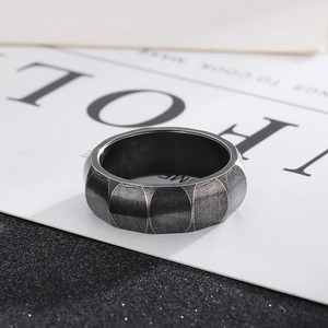 Macro view of wide dark grey titanium steel ring with industrial oval brushed texture