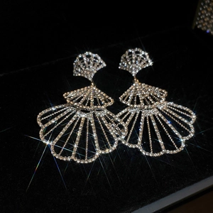 Macro shot of large shell shaped fan earrings with sparkling rhinestones on black background