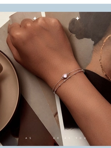 Close-up of a double-layer silver bracelet with a pink heart gemstone worn on wrist