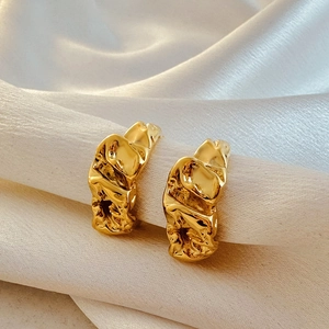 Macro detail of 18k gold C-shape croissant earrings with textured irregular lava design